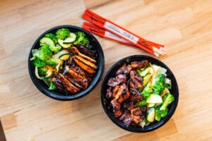A picture of two spicy chicken teriyaki bowls with veggies